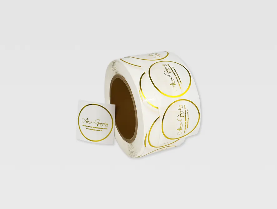 Multiple rolls of circular transparent gold foil labels arranged on a white background