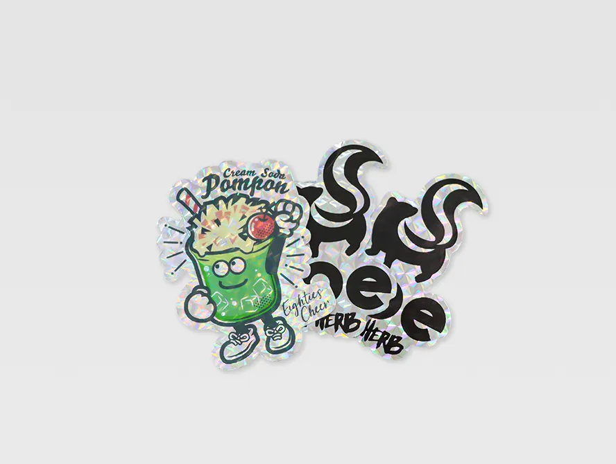 Two custom glitter stickers with bold illustrations on flat surface